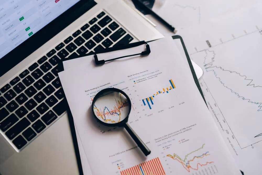 Magnifying glass on financial charts and graphs with laptop keyboard